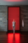 Person standing in front of massive full-body red light therapy panel in luxury spa